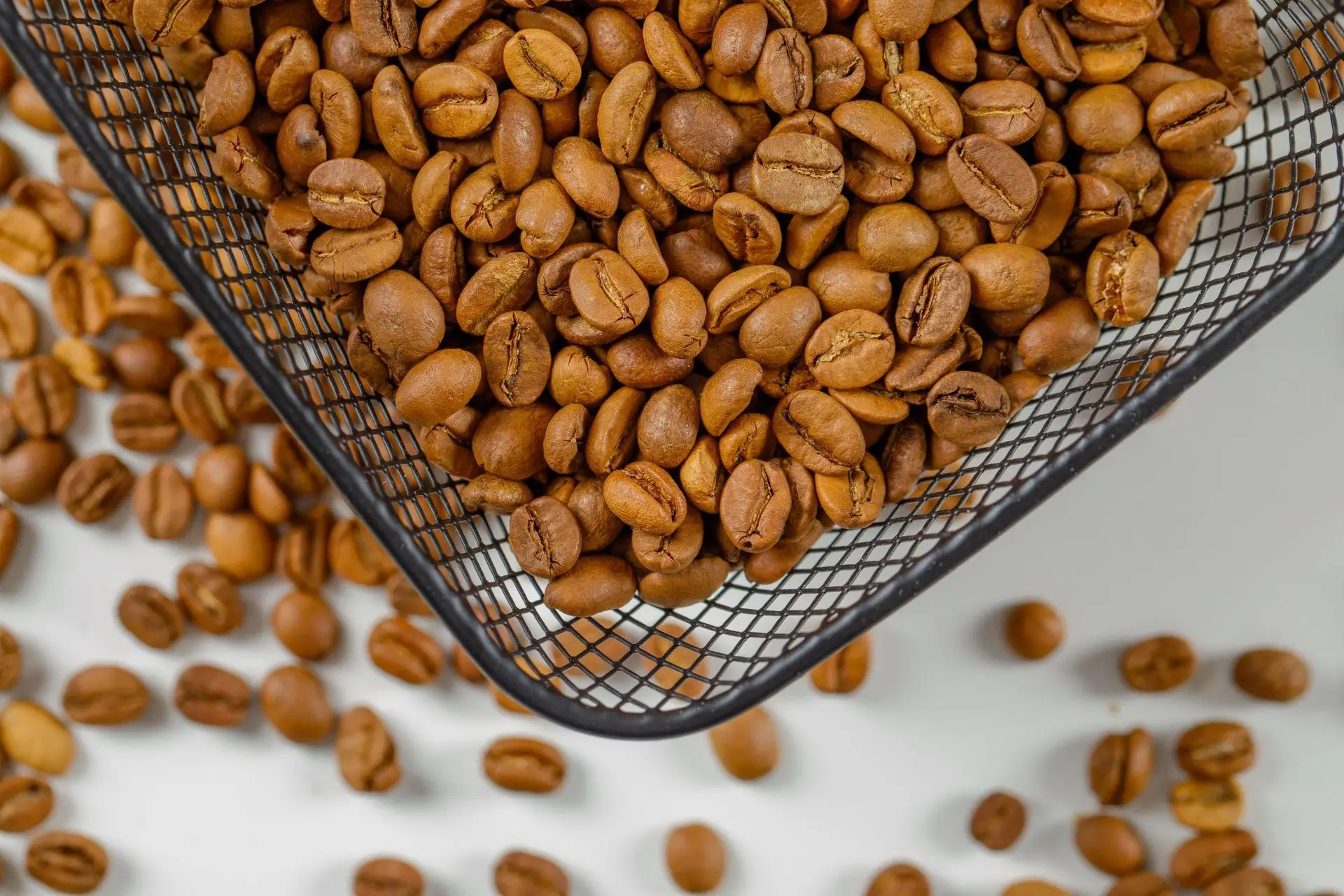 Roasted coffee beans in basket and on surface